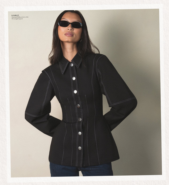 Woman wearing a black jacket with white buttons against a neutral background